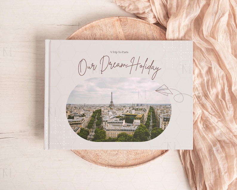 May include: A white photo album with a gray background and a photo of the Eiffel Tower in Paris. The album has the text "A Trip to Paris. Our Dream Holiday" on the front.