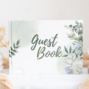 May include: A white guest book with a green watercolor background and floral illustrations. The text "Guest Book" is written in black cursive font.