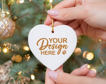 May include: White ceramic heart-shaped Christmas ornament with gold string and the text "YOUR Design HERE" in gold lettering. A paw print is next to the text.