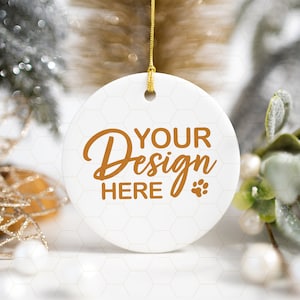 May include: White ceramic ornament with a gold string for hanging. The ornament has a hexagonal pattern and the text "YOUR Design HERE" in brown lettering.