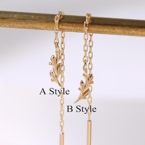 May include: Gold-colored earrings with a leaf design and a dangling bar. The earrings are shown in two styles, labeled "A Style" and "B Style". The earrings are hanging from a gold-colored bar.