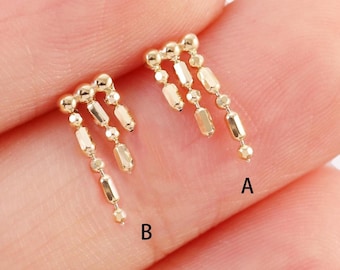 May include: Two gold dangle earrings with a chain of small round beads and rectangular beads hanging from each earring. The earrings are labeled A and B.