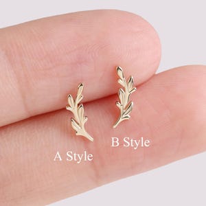 May include: Two small, gold-colored leaf-shaped earrings. One earring is labeled "A Style" and the other is labeled "B Style". The earrings are displayed on a light pink background.
