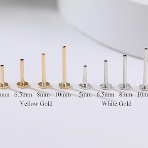 Może przedstawiać: Kolekcja złotych i białych złotych kolczyków z płaskim tyłem w różnych rozmiarach. Złote kolczyki są oznaczone 5 mm, 6,5 mm, 8 mm i 10 mm. Białe złote kolczyki są oznaczone 5 mm, 6,5 mm, 8 mm i 10 mm.