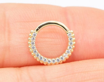 May include: Gold hoop earring with a row of clear cubic zirconia stones around the edge.
