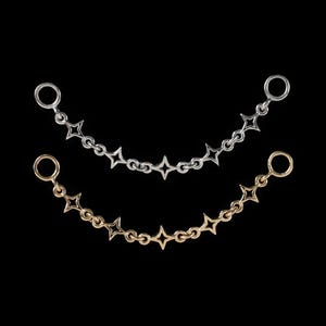 May include: Two decorative metal chains, one silver-toned and one gold-toned, each featuring a series of four-pointed star-shaped links connected by small circular rings, with a larger circular ring at each end of the chain for attachment.