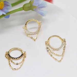 May include: Two gold hoop earrings with dangling chains. One hoop has clear stones and the other has black stones.