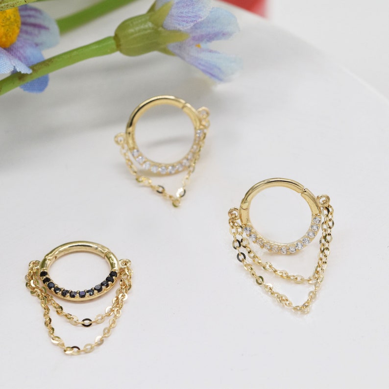 May include: Two gold hoop earrings with dangling chains. One hoop has clear stones and the other has black stones.