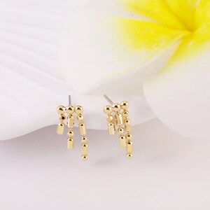May include: A pair of gold-toned dangle earrings with a chain of small round and rectangular beads.
