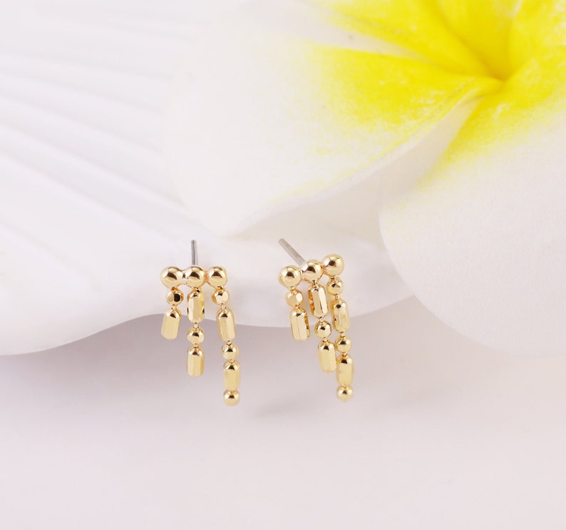 May include: A pair of gold-toned dangle earrings with a chain of small round and rectangular beads.