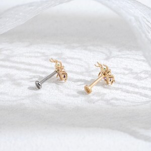 May include: Two gold scorpion body jewelry pieces with clear and purple gemstones. The jewelry is on a white surface.