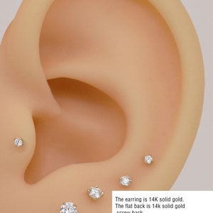 May include: A close-up of a gold earring with a small diamond. The earring is available in three sizes: 10mm, 8mm, and 6.5mm. The earring is made of 14k solid gold and has a flat back.