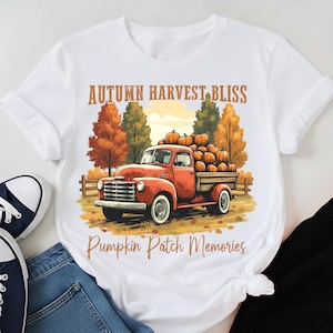 May include: White t-shirt featuring a vintage red truck filled with pumpkins, set against a fall landscape. The shirt has the text "Autumn Harvest Bliss" and "Pumpkin Patch Memories" in a warm, autumnal color palette.