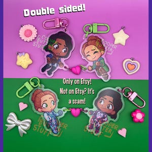 May include: Two double-sided acrylic keychains featuring chibi-style characters connected by a pink heart charm. The set includes small charms shaped like stars, flowers, hearts, and a bow. Text reads: Double sided! Only on Etsy! Not on Etsy? It's a scam!