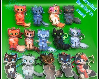 May include: A collection of fourteen acrylic cat keychains in various colours and patterns, including orange, blue, black, calico, and tabby designs. Each keychain features a cartoon-style cat with large eyes and a metal attachment ring.