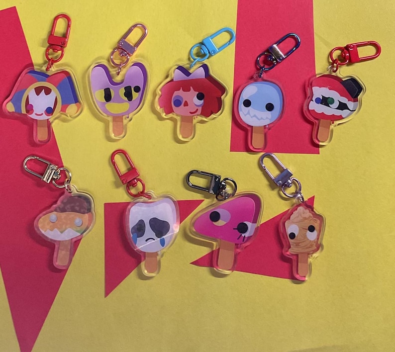 Puede incluir: Una colecci&oacute;n de nueve llaveros de acr&iacute;lico con forma de diversos helados de palo con caras de personajes coloridos. Cada llavero cuenta con un cierre de mosquet&oacute;n de metal en colores como rojo, azul, plateado y rosa, unido a un dije de acr&iacute;lico.