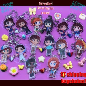 May include: A collection of acrylic character keychains featuring chibi-style figures, accompanied by small charms shaped like stars, flowers, bows, and food. Text on the image reads: Only on Etsy! Not on Etsy? It's a scam! and ST shipping keychains!