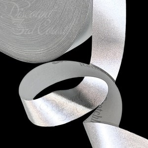 May include: A roll of silver reflective tape. The tape is rolled up and the end is curled into a loop.