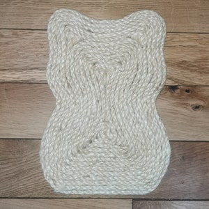 K&ouml;nnte beinhalten: Ein wei&szlig;er, geflochtener Seil-Teppich mit einer einzigartigen, organischen Form. Der Teppich ist aus Naturfasern gefertigt und hat eine strukturierte Oberfl&auml;che.