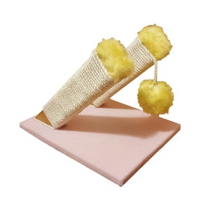 May include: A pink cat scratching post with two sisal-covered posts and yellow fuzzy pom-poms.
