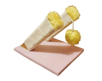 May include: A pink cat scratching post with two sisal-covered posts and yellow fuzzy pom-poms.
