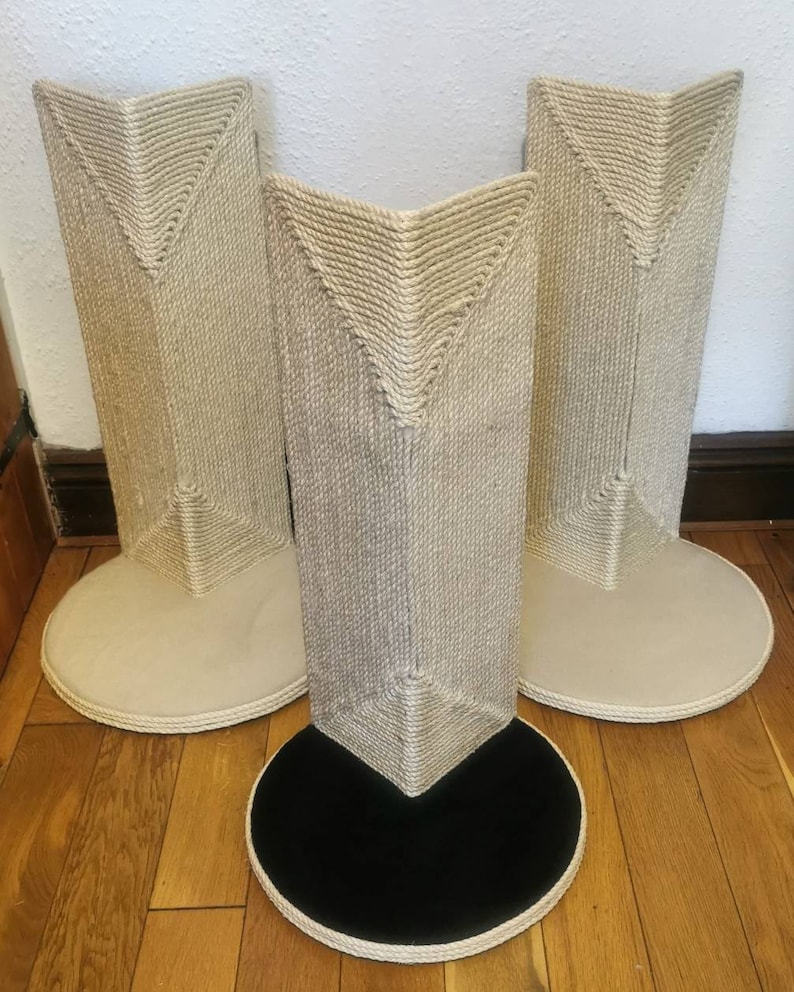 May include: Three beige cat scratching posts with a rope-covered surface. The posts have a triangular shape and a round base. The base of the center post is black.