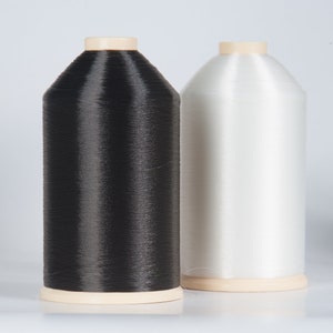 Könnte beinhalten: Zwei Garnrollen, eine schwarze und eine weiße, werden vor einem weißen Hintergrund gezeigt. Die Rollen sind aus Kunststoff und haben eine beige Basis.