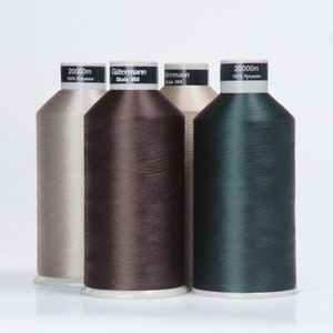 Può includere: Tre bobine di filo Gutermann Skala 360, ciascuna lunga 2000 m. Le bobine sono beige, marrone e verde scuro.