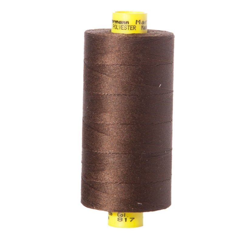 May include: A spool of brown polyester thread with a yellow label that reads "Made in Germany" and "Polyester". The label also has the color number "817" printed on it.