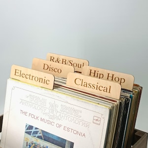 May include: A collection of vinyl records with wooden dividers. The dividers are labelled 'Electronic', 'Disco', 'R&B/Soul', 'Hip Hop', and 'Classical'. The record sleeves are labelled 'Anthology' and 'The Folk Music of Estonia'.
