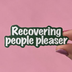 May include: Green sticker with white text that reads "recovering people pleaser".