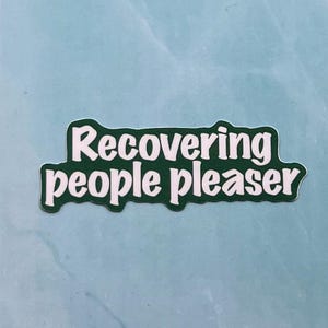 May include: Green sticker with white text that reads "Recovering people pleaser".