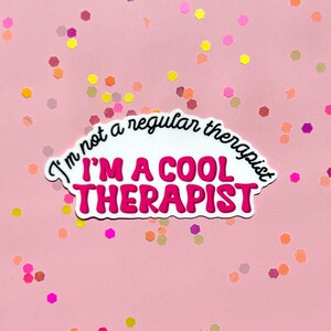 May include: White sticker with pink text that reads "I'm not a regular therapist I'm a cool therapist". The sticker is on a pink background with colourful confetti.