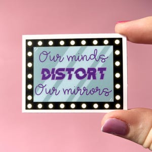 Könnte beinhalten: Ein Aufkleber mit einem weißen Rand und einem schwarzen Rahmen mit weißen Lichtern drumherum. Der Hintergrund ist hellblau mit weißen Streifen. Der Text lautet "Our minds DISTORT Our mirrors".