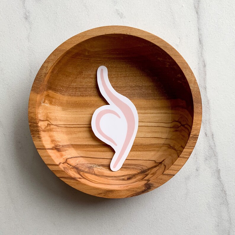 May include: A pink and white sticker of a hand making the 'okay' sign, placed on a wooden bowl.