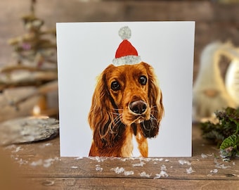 May include: A square greeting card featuring a detailed illustration of a Cocker Spaniel wearing a red Santa hat with a white pom-pom. The dog has long, brown fur and a gentle expression, perfect for holiday greetings.