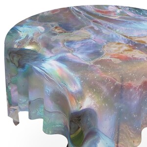 May include: A round tablecloth with a swirling iridescent pattern in shades of blue, purple, and brown. The tablecloth is draped over a black table with four legs.