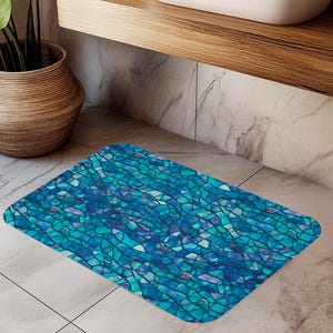 Puede incluir: Una alfombra de baño de mosaico azul y morado con un patrón geométrico. La alfombra está hecha de un material suave y absorbente y es perfecta para agregar un toque de estilo a tu baño.