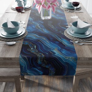May include: A blue and gold table runner with a marbled pattern. The runner is on a wooden table with place settings on either side.