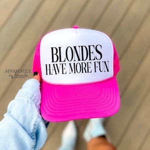 May include: A pink and white trucker hat with the text "Blondes Have More Fun" in black.