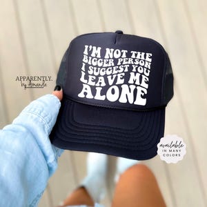 May include: Black trucker hat with white text that reads "I'm not the bigger person I suggest you leave me alone" in a retro font. The hat is available in many colors.