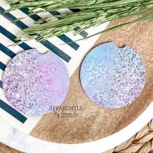 May include: Two round car coasters with a glittery, leopard print design. One coaster is lavender and pink, the other is blue and purple. The text "Apparently. by Amanda" is visible on the bottom right.