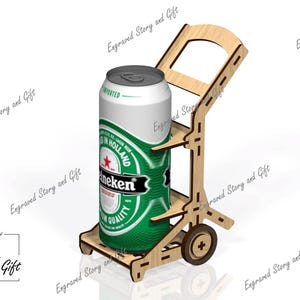 Puede incluir: Un soporte para bebidas de madera clara diseñado para transportar una sola lata de aluminio alta. La estructura cuenta con un asa, dos ruedas pequeñas en los laterales y una base plana para sostener la lata. La madera tiene juntas cortadas con láser visibles.