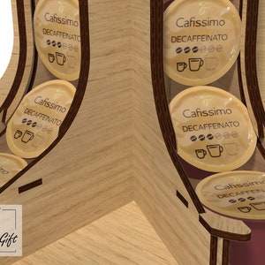 May include: A wooden coffee pod holder with a circular design. The holder is filled with coffee pods labelled "Cafissimo Decaffeinato".