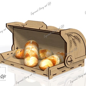May include: A light-coloured wooden bread bin with a curved, hinged lid featuring an engraved wheat stalk design on the side panel. The interior contains several small, golden-brown bread rolls. The text Engraved Story and Gift is visible.