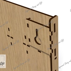 May include: Close-up of a wooden wall hanging with a keyhole-shaped cutout for hanging. The piece is made of light-colored wood with a dark brown border and the text "Story & Gift".
