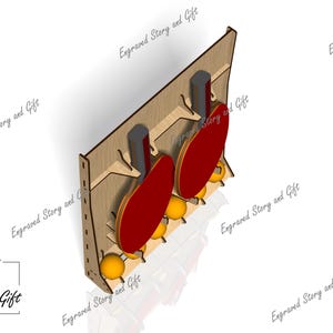 May include: Wooden ping pong paddle and ball holder. The holder is made of light brown wood and features two red paddles and several yellow balls. The text "Engraved Story and Gift" is visible.