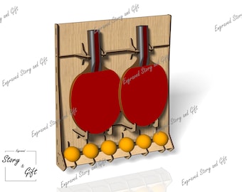 May include: Wooden ping pong paddle and ball holder. The holder is made of light brown wood and features two red paddles and six yellow balls. The text "Engraved Story and Gift" is visible.