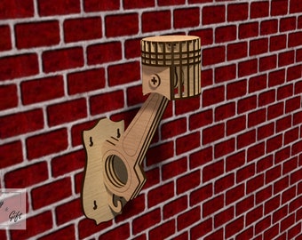 May include: A wooden wall-mounted shelf shaped like a car engine piston. The shelf is made of light brown wood and has a metal screw in the centre. The shelf is mounted on a red brick wall.