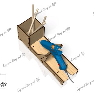 K&ouml;nnte beinhalten: Ein Holzst&auml;nder mit einem Fach zur Aufbewahrung von Klebestiften und einem Schlitz f&uuml;r eine Hei&szlig;klebepistole. Die Hei&szlig;klebepistole ist blau und schwarz und hat ein Kabel.